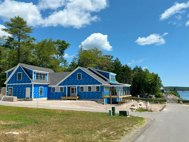 New coastal home wrapped in a protective blue weather barrier with installed windows.