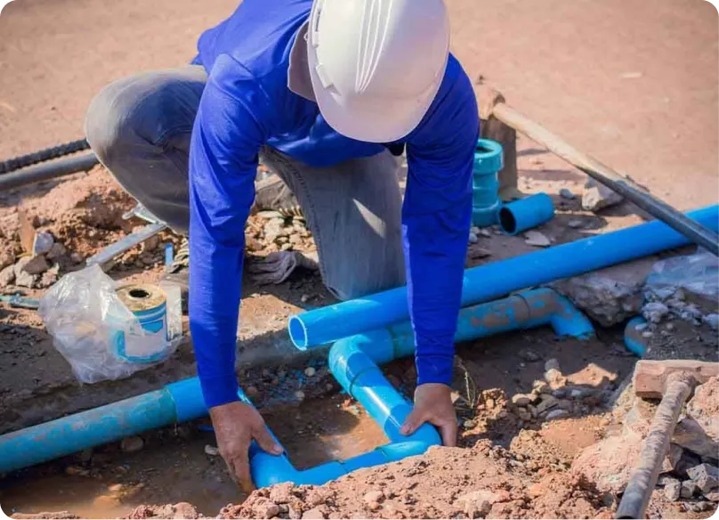Worker connecting blue underground water lines