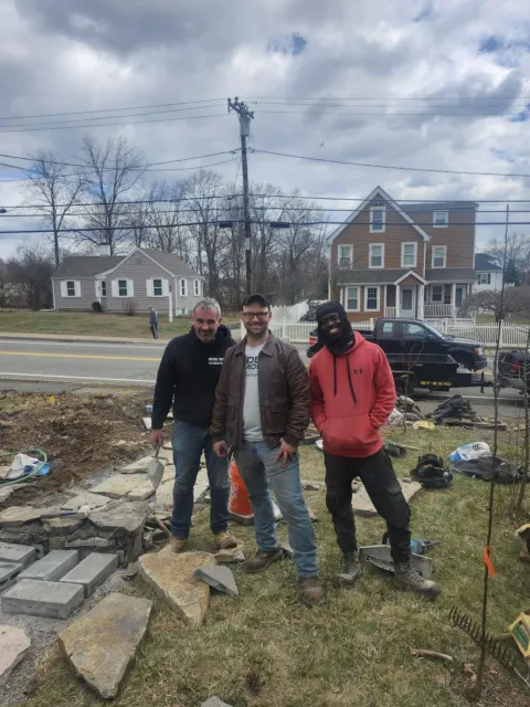 Three Rockhound Masonry team members outside of a work site for a brick walkway and stairs in Norfolk County, MA.