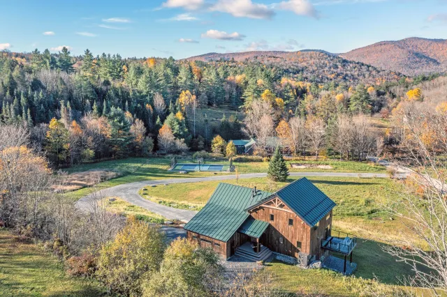 Timber frame home in Rochester, Vermont, surrounded by autumn woods and open meadows.