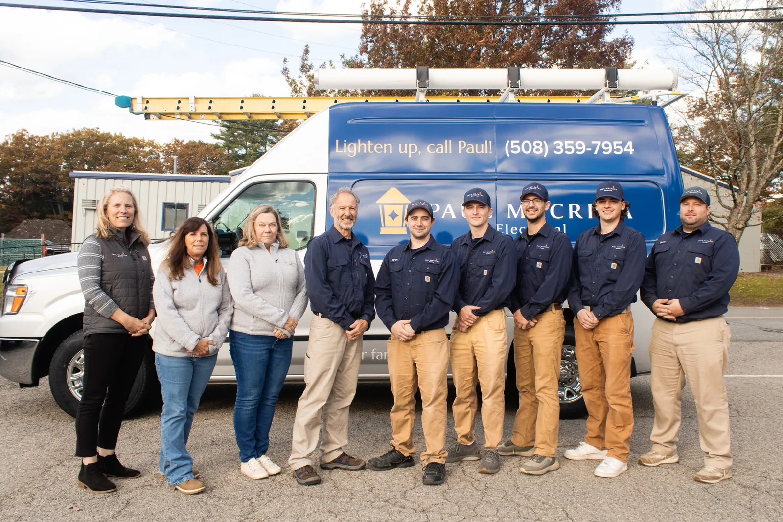 Paul Macrina Electrical team posing in front of blue service van with ladder rack