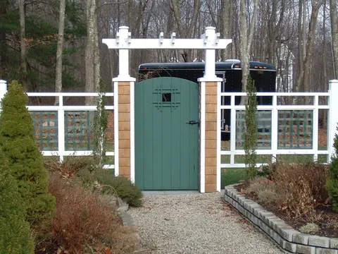 custom white and green wooden fence and entryway to a backyard