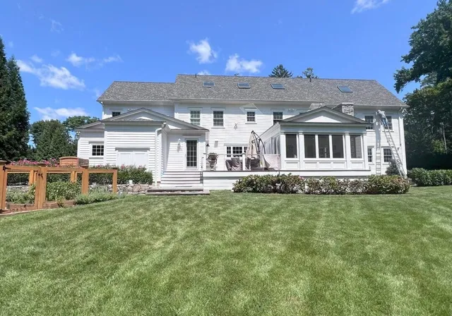 A large white house with a spacious green lawn under a clear blue sky.