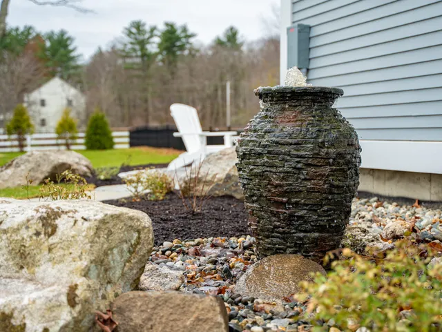 Stone urn fountain in landscaped backyard garden