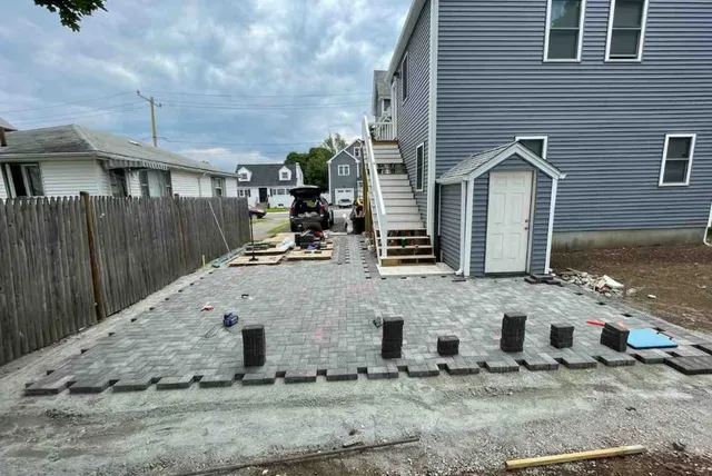 stone patio pavers being installed next to gray house in Boston
