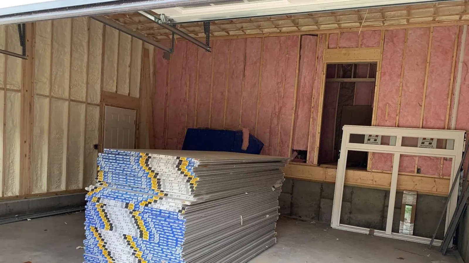A stack of drywall is sitting in a garage under construction.