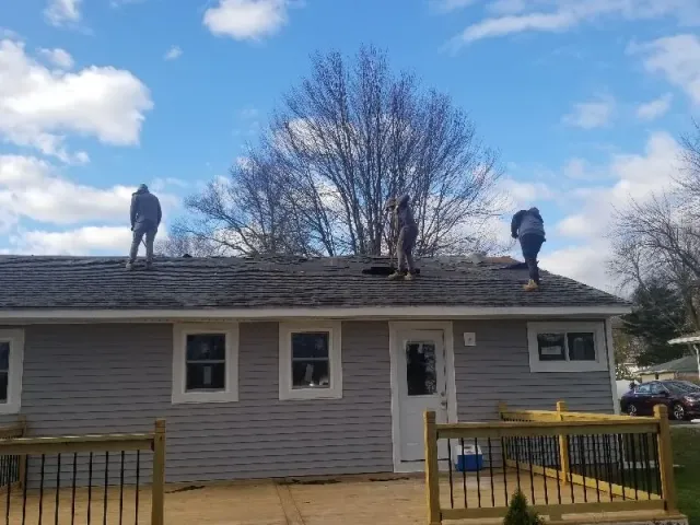 Two men are working on the roof of a house.