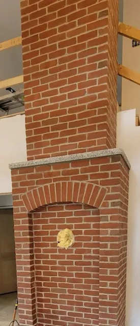 A brick fireplace under construction with insulation visible through an opening in the front.