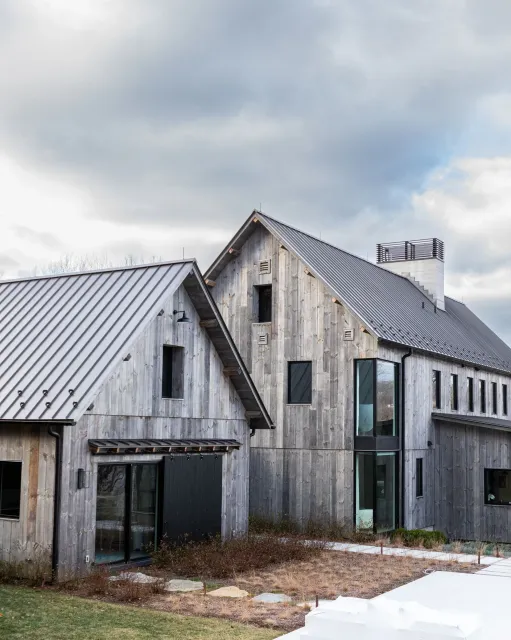 A large wooden house with a metal roof is sitting on top of a snow covered field.
