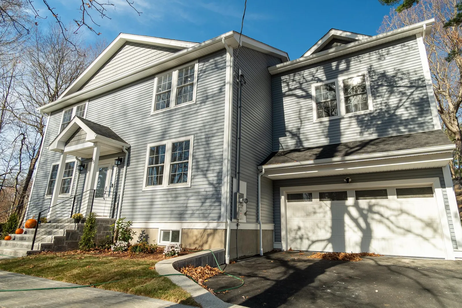 A stylish gray house with a garage and driveway, highlighting contemporary exterior design in new home construction.