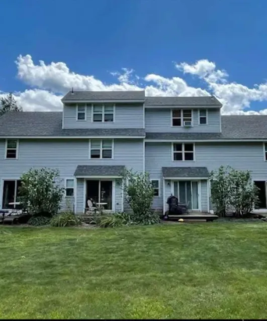 Two-story house with bushes and lawn.