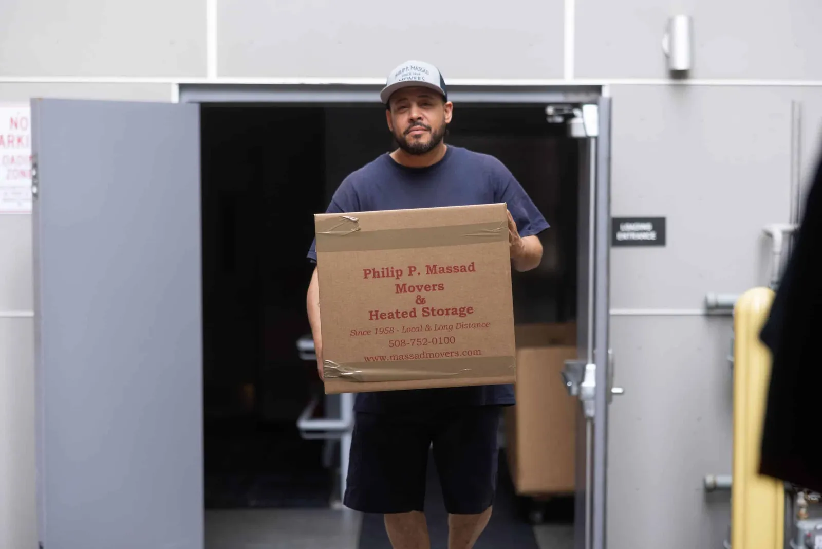 A man carrying a box into a warehouse.