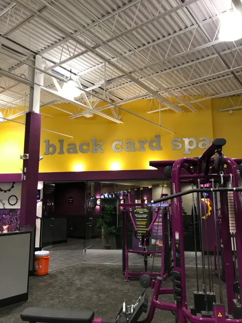 Inside a gym called 'Black Card Spa' with purple workout equipment, a sign with fitness instructions, and a yellow wall with the gym's name in large letters.