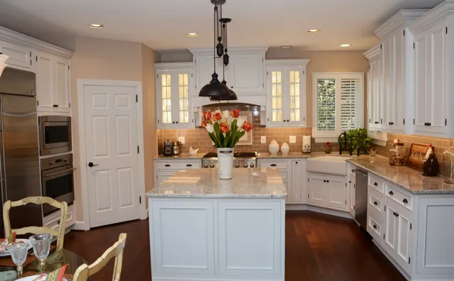 White kitchen with island, granite counters and glass upper cabinets
