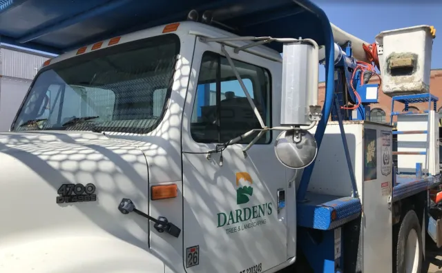 White Darden's truck with a bucket for aerial work. Blue accents, sunny setting.