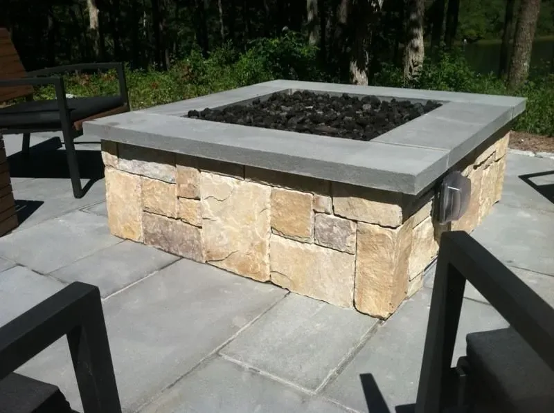 A fire pit is surrounded by chairs on a patio