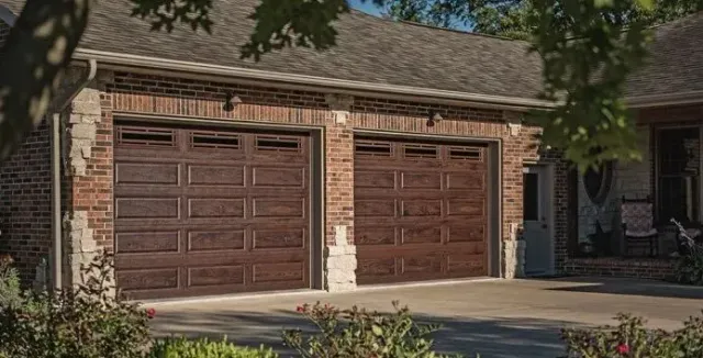 Suburban home with a two-car brown garage and a driveway shaded by trees