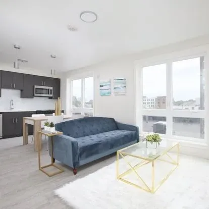 A living room with a blue couch and a glass coffee table.