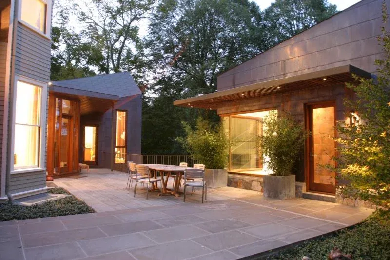 Contemporary addition with copper cladding and bluestone terrace at dusk