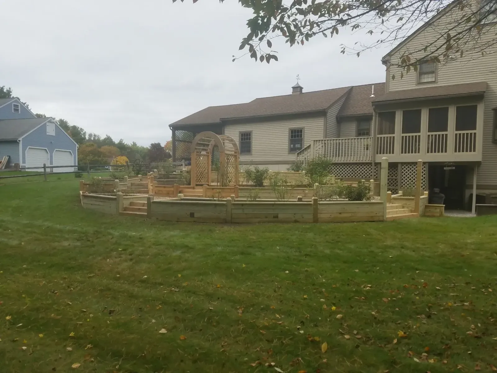 Backyard garden with raised beds, a stone fountain, and a house with a covered porch