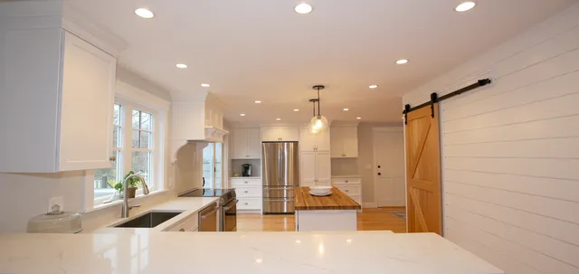 Renovated white kitchen with butcher-block island and barn door
