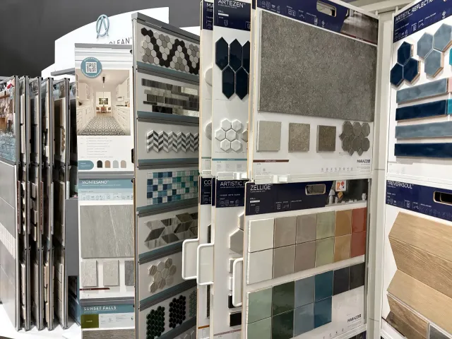 Tile display racks with assorted mosaic and stone samples in a showroom