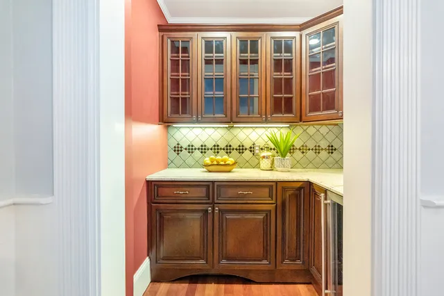 Butler's pantry with glass-front cabinetry and stone counter