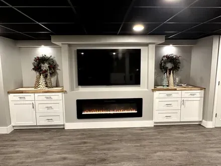 Modern living room with a wall-mounted TV, electric fireplace, and two decorated white cabinets
