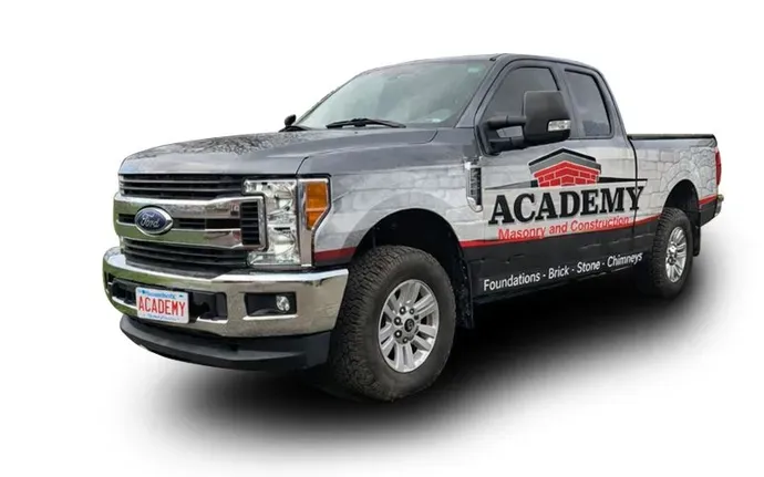 A grey Ford pickup truck branded with 'Academy Masonry and Construction' logos and text on its side.