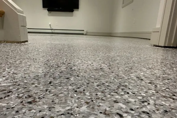 Close-up of a durable, speckled garage floor coating in shades of gray, white, and black. This garage floor installation offers a seamless and stylish surface.