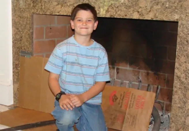 Benjamin Albano, son of Northeast Chimney Sweeps' CEO, smiling while helping with a chimney cleaning project.