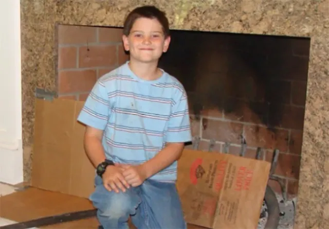 Benjamin Albano, son of Northeast Chimney Sweeps' CEO, smiling while helping with a chimney cleaning project.
