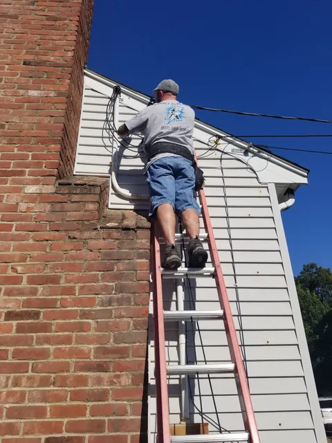 Kinney Electric technician running exterior service wiring on a Woburn-area home