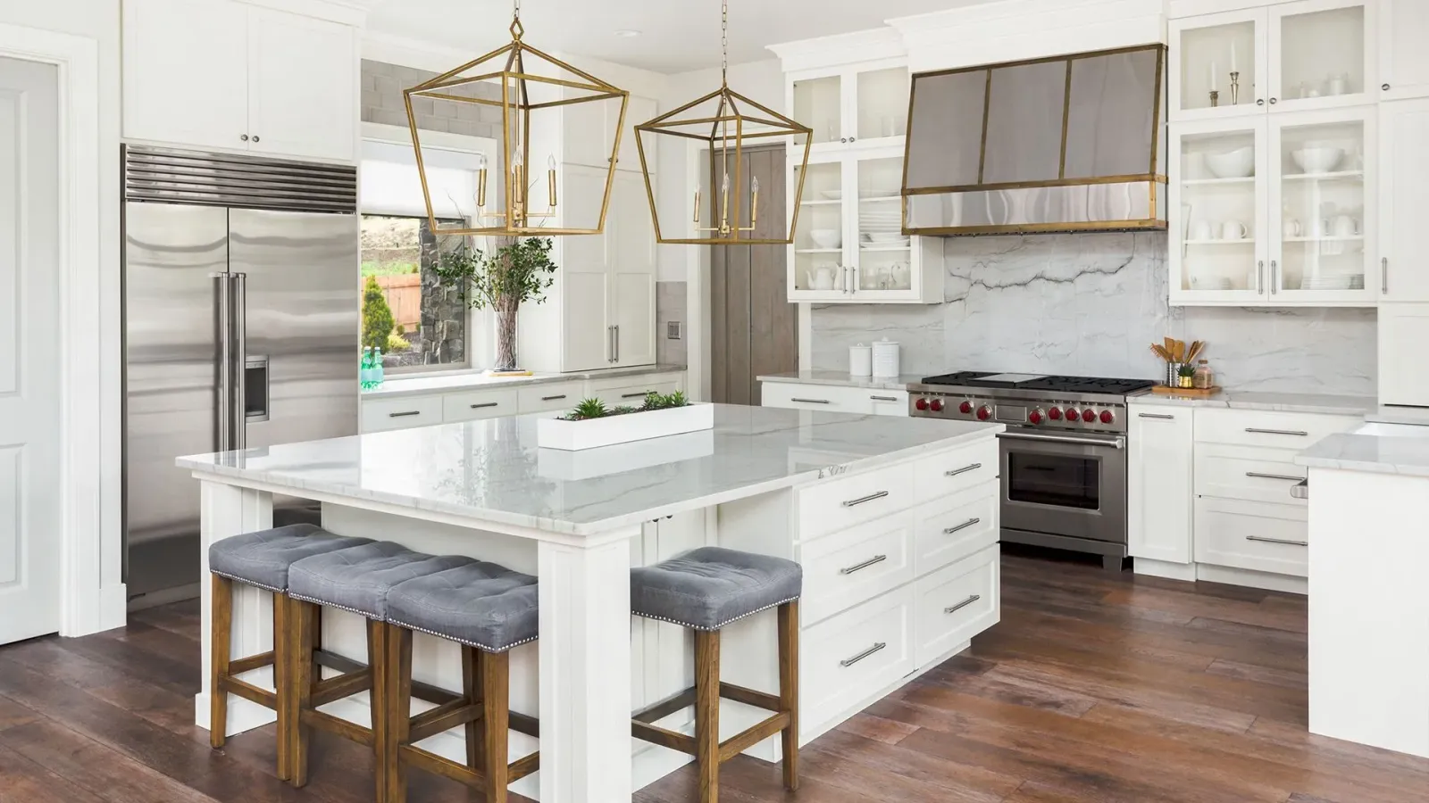 Bright modern kitchen with white cabinets, island, stainless steel appliances, and gray stools