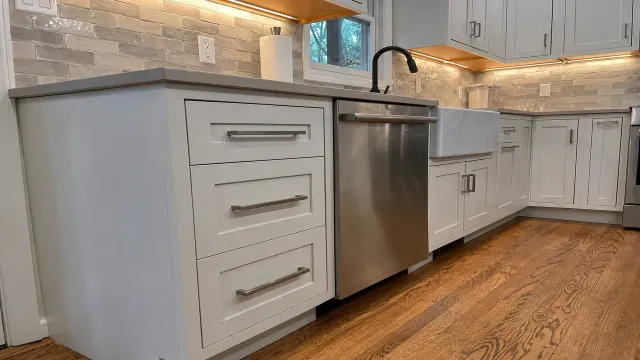 Modern white kitchen with stainless steel dishwasher and wood flooring