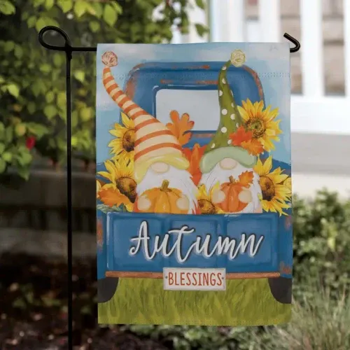 Colorful autumn garden flag featuring two whimsical fall gnomes holding pumpkins in the bed of a vintage blue truck surrounded by bright sunflowers and fall leaves with the words "Autumn Blessings."