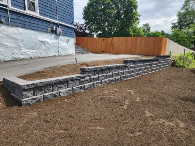 a stone wall is being built in front of a blue house