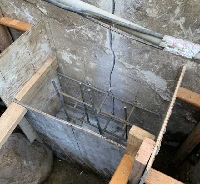 Foundation repair and reinforcement work inside a concrete footing excavation
