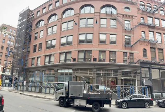 A truck is parked in front of a large brick building.
