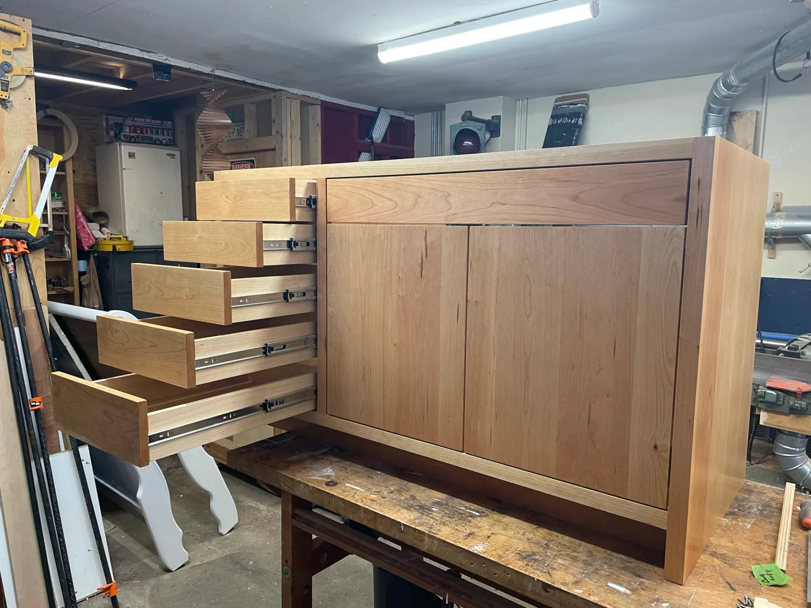 unfinished wooden cabinet with multiple drawers in a woodworking workshop