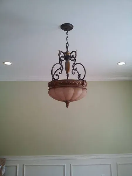 Ornate chandelier hanging from a white ceiling, above a light green wall.