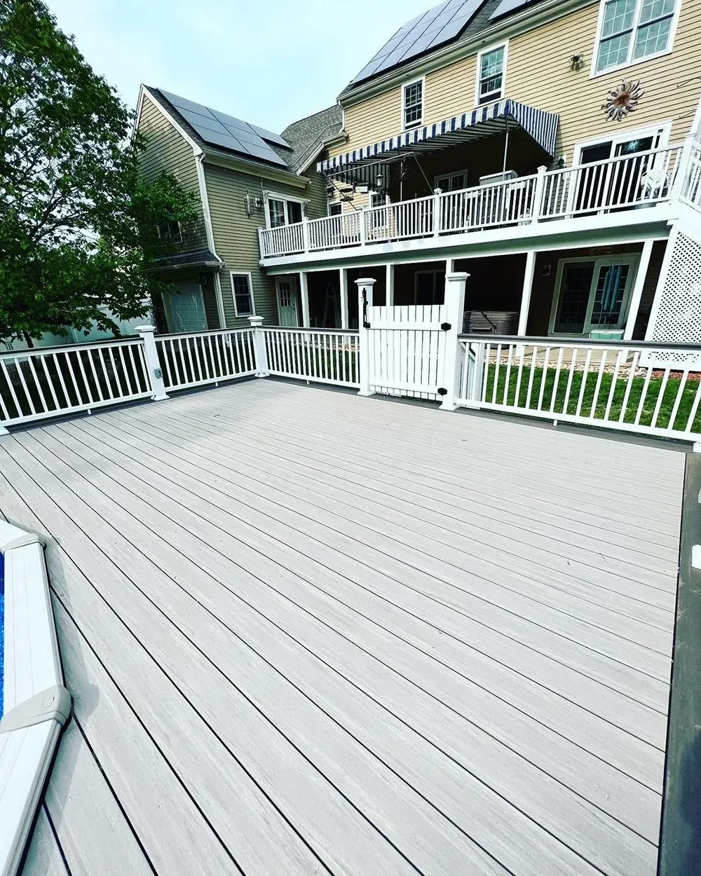A large deck with a white railing and a house in the background