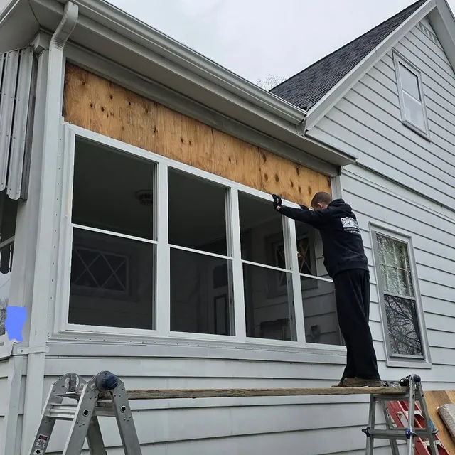 Crew member installing sheathing on a porch enclosure