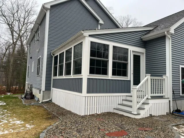The back of a house with a screened in porch and stairs.