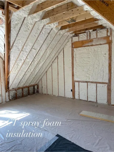 Interior of an unfinished room with spray foam insulation on the walls and ceiling.