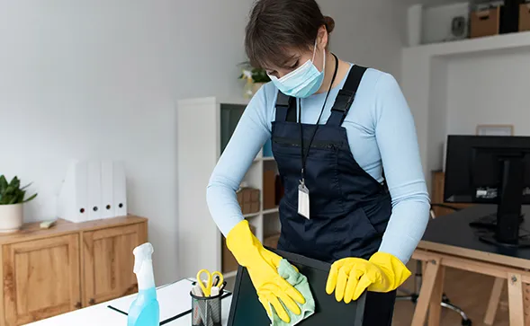 Cleaner making a bed with fresh white linens in a bright bedroom
