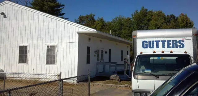 A white, single-story building sits next to a truck with