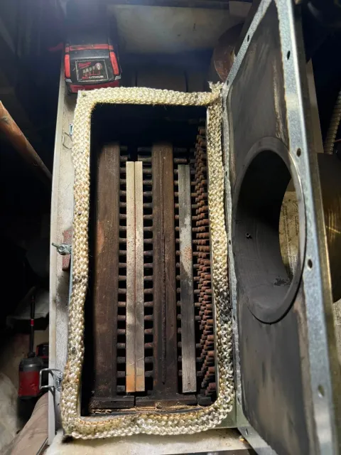 Industrial machine interior with rusted metal slats and a red control box at the top left