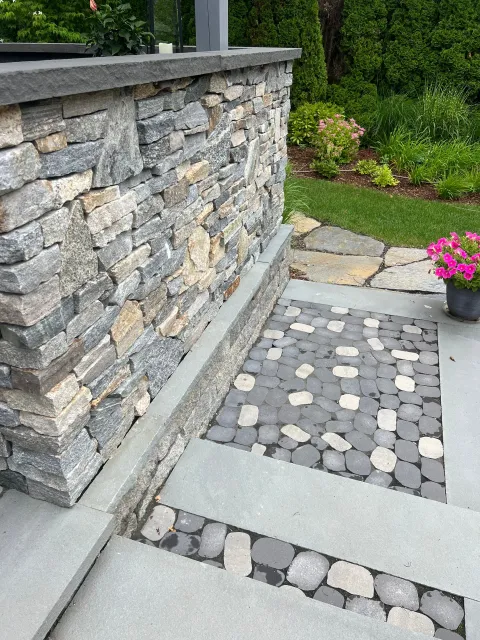 A stone wall with steps leading up to it in a garden.