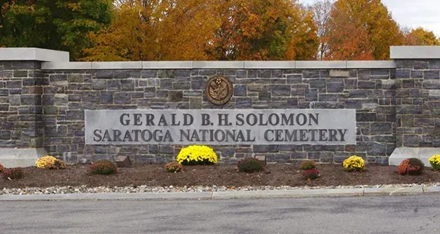 A stone wall with a sign that says gerald b.h. solomon saratoga national cemetery